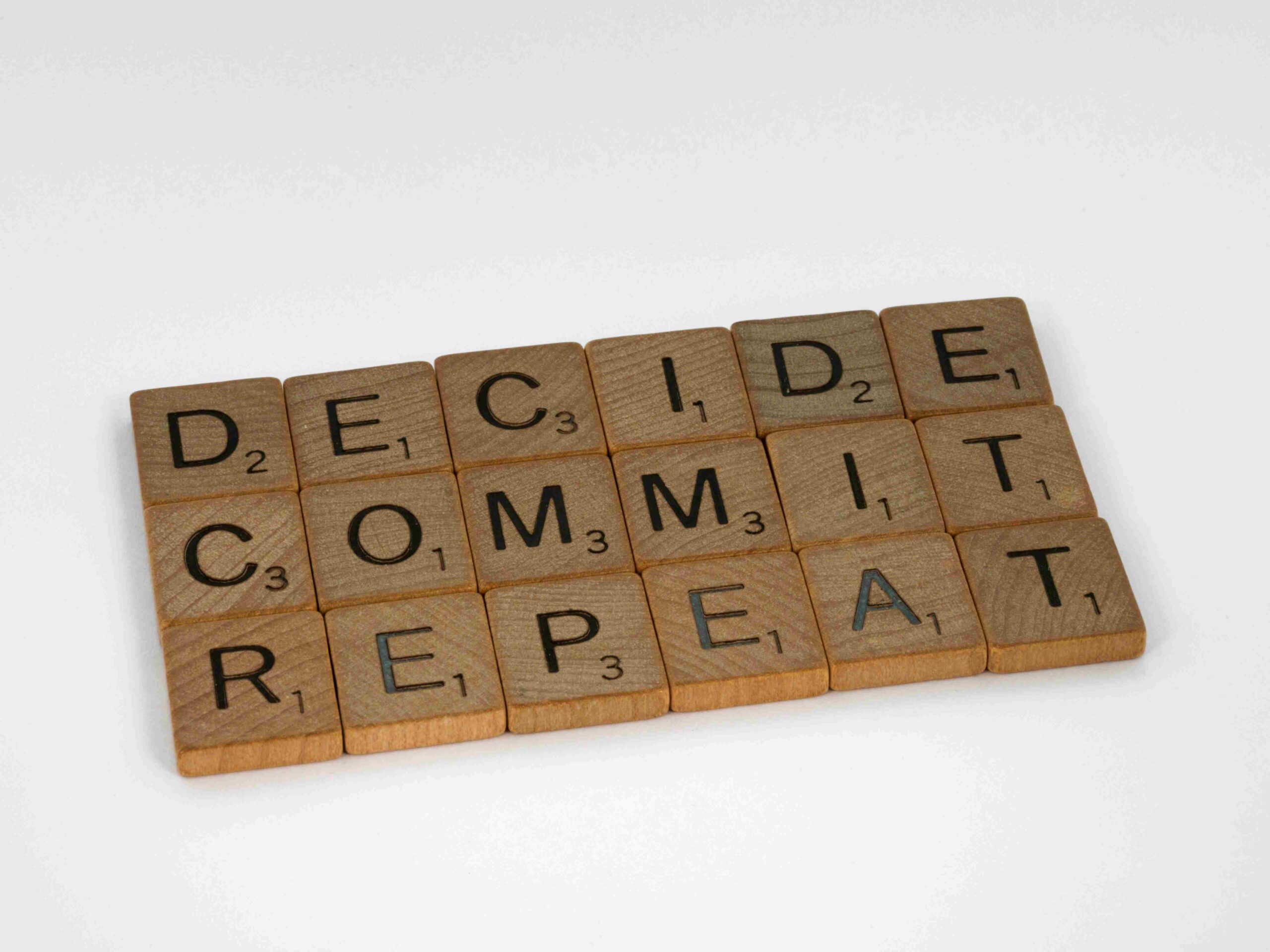 Tessere di Scrabble con le parole "Decide, Commit, Repeat": il rinnovo del marchio ogni 10 anni